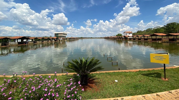 Lago do Clube Pescar com quiosques de pesca nas margens e placa de aviso