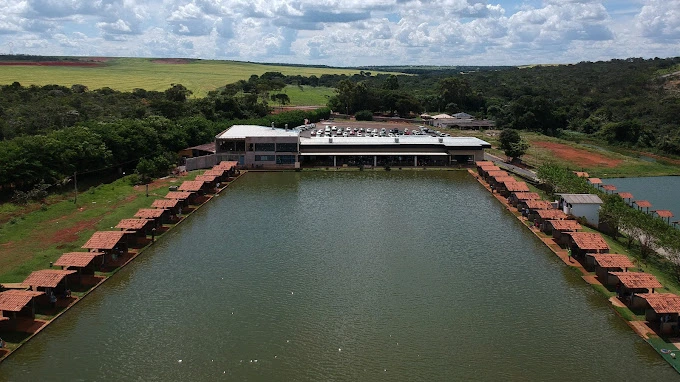 Vista aérea do lago retangular do Clube Pescar cercado por chalés e pelo restaurante